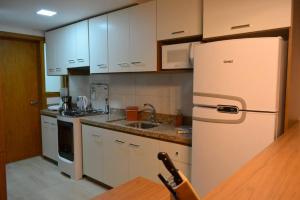 cocina con armarios blancos y nevera blanca en LOCAR-IN GRAMADO Residencial Garibaldi Centro, en Gramado