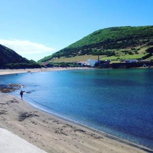 une personne marchant sur une plage près de l'eau dans l'établissement Baía das Caldeirinhas, à Horta