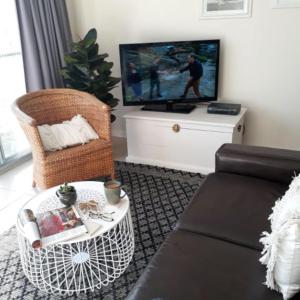 a living room with a couch and a tv at Shutters by the Sea-Oceanfront-Sea views-Private retreat for 2 in Kiama