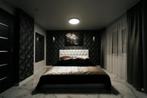 1 dormitorio con 1 cama con pared negra en Kiss Apartment, en Šilutė