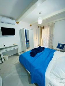 Schlafzimmer mit einem blauen Bett und einem TV in der Unterkunft Casa 68 Ortigia in Syrakus
