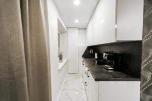 a kitchen with white cabinets and a black counter top at Kiss Apartment in Šilutė