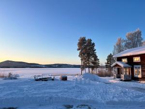 a cabin in the snow next to a lake at Trevlig villa mellan sjöarna i Vistträsk By. in Vistheden