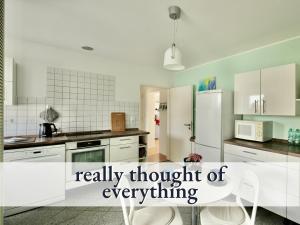 eine Küche mit weißen Schränken und einem weißen Kühlschrank in der Unterkunft Komfortables bestens ausgestattetes Appartement Nähe Karlsruhe & KIT in Linkenheim-Hochstetten