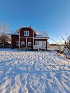 una casa roja con nieve en el suelo delante de ella en Röda villan 
