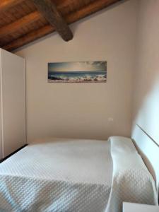1 dormitorio con 1 cama blanca y una pintura en la pared en Green House 2.0, en Pieve di Teco