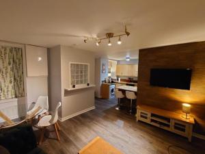 a living room with a couch and a television and a kitchen at The Black Isle Retreat in Inverness