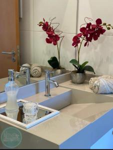lavabo en el baño con una botella de jabón y flores en Velutti Encantos do Mar, VISTA MAR, PREMIUM, PENHA, Beto Carrero World, en Penha