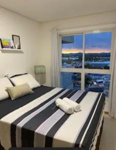 ein Schlafzimmer mit einem großen Bett und einem großen Fenster in der Unterkunft Velutti Encantos do Mar, VISTA MAR, PREMIUM, PENHA, Beto Carrero World in Penha