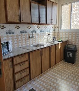 a kitchen with wooden cabinets and a sink at Farah Hotel Apartment in Muscat