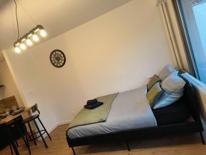 a bed in a room with a clock on the wall at Charmant studio - Gare colmar in Colmar