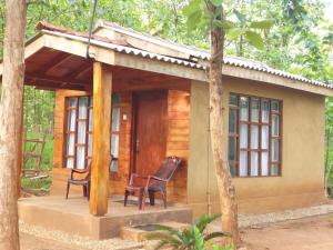 una pequeña cabaña con 2 sillas delante en Mini Jungle Canopy Udawalawe, en Udawalawe