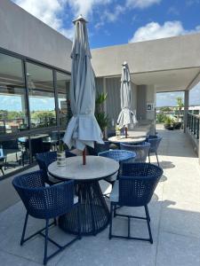 un patio al aire libre con mesas, sillas y sombrillas en Porto Galinhas frente mar Mikonos en Ipojuca