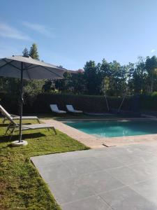 una sombrilla y sillas junto a la piscina en Villa Sara avec sa piscine et jardin, en Marrakech