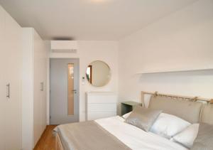 a white bedroom with a bed and a mirror at EFI Residence Holzova 28 in Brno