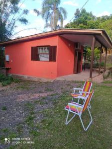 twee stoelen voor een rood huis bij Casa Hermosa in Igrejinha