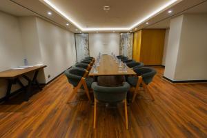 een vergaderzaal met een lange tafel en stoelen bij The Grand Lux Hotel in Doha