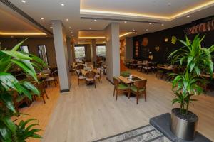 un ristorante con tavoli, sedie e piante di The Grand Lux Hotel a Doha