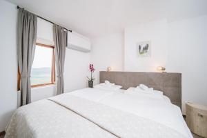 a white bedroom with a large bed and a window at Villa Borgo B&B in Motovun