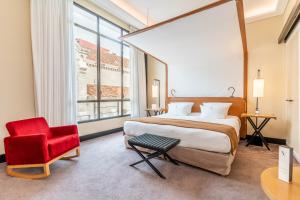 a bedroom with a large bed and a red chair at Five Seas by Inwood Hotels in Cannes