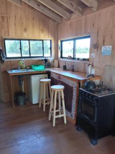 una cucina con piano cottura e bancone con sgabelli di Casa de campo cerca del Cabo a Rincón de los Oliveras