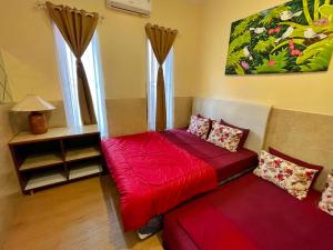 タンゲランにあるTAMA Guesthouse 15 People for Family or Groupの赤いベッドとソファが備わる客室です。