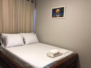 uma cama com almofadas brancas e uma fotografia na parede em Apartamento em Luís Correia em Luis Correia