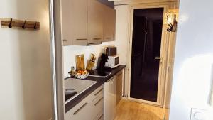 a small kitchen with white cabinets and a microwave at Le Cocon Cap Forêt in Lège-Cap-Ferret