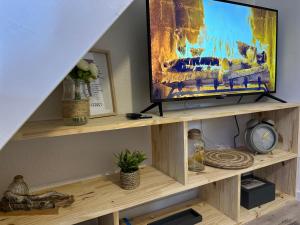 - une télévision installée au-dessus d'une étagère en bois dans l'établissement Le Cocon Cap Forêt, à Lège-Cap-Ferret