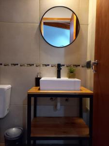 Un baño con un lavabo blanco y un espejo. en Departamento 2448, en Mina Clavero