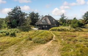 a black hut with a thatched roof in a field at Holiday Home Lærkestien in Skagen