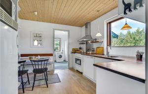 cocina con armarios blancos, mesa y ventana en 3 Bedroom Awesome Home In Hjrring, en Hjørring