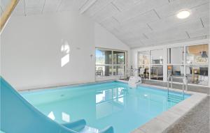 a large swimming pool with blue water in a building at Lovely Home In Bindslev With Sauna in Bindslev