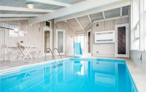 a large swimming pool in a room with a table at Amazing Home In Hjrring With 3 Bedrooms, Sauna And Private Swimming Pool in Lønstrup
