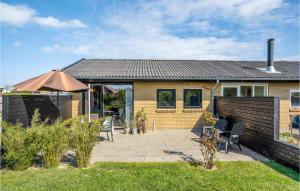 a house with a patio with chairs and an umbrella at Nice Home In Skagen With Wifi in Skagen