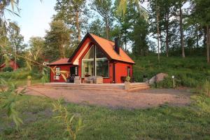 a red cabin with a large window in a forest at Lovely house on beautiful private lakeside estate! in Bunn