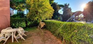 a table and chairs sitting next to a hedge at Casa Silvia a due passi dal mare in Cavallino-Treporti