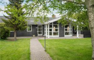 a black house with a lawn in front of it at 4 Bedroom Amazing Home In Hjrring in Lønstrup