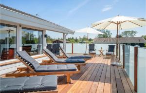 a wooden deck with lounge chairs and an umbrella at Nice Home In Bindslev With 4 Bedrooms, Sauna And Indoor Swimming Pool in Bindslev