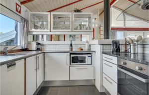 a kitchen with white cabinets and a microwave at Nice Home In Bindslev With 4 Bedrooms, Sauna And Indoor Swimming Pool in Bindslev