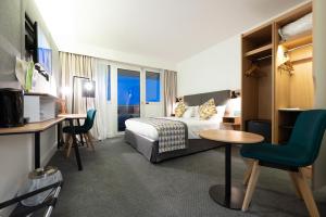 Habitación de hotel con cama, mesa y sillas en Holiday Inn Calais-Centre, an IHG Hotel, en Calais