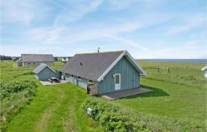 a green barn in a field with the ocean in the background at Beautiful Home In Hjrring With 3 Bedrooms And Wifi in Lønstrup