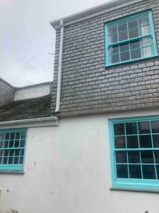 a white house with blue windows and a roof at 2-bedroom cottage in heart of St Ives w/ parking in St Ives
