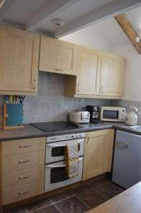 a kitchen with white appliances and wooden cabinets at 2-bedroom cottage in heart of St Ives w/ parking in St Ives