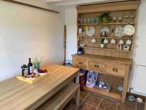 a kitchen with a wooden table and a shelf with dishes at 2-bedroom cottage in heart of St Ives w/ parking in St Ives