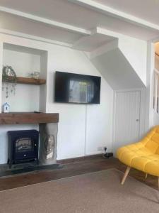 een woonkamer met een open haard en een gele bank bij 2-bedroom cottage in heart of St Ives w/ parking in St Ives