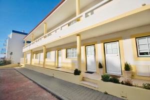 un edificio amarillo con puertas y ventanas blancas en Catarina House - Baleal Beach, Balcony, Pool, en Ferrel