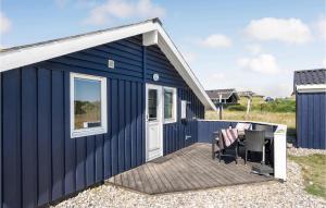 a blue shed with a deck and a chair at Amazing Home In Hvide Sande With Sauna in Havrvig