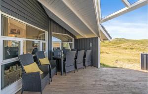 a covered deck with chairs and a table on a house at Holiday Home Arvidvej Denm in Bjerregård