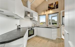 a kitchen with white cabinets and a large window at Holiday Home Arvidvej Denm in Bjerregård